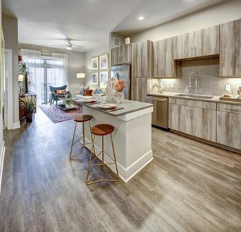 A kitchen with a white island and wooden cabinets at Arise Riverside Apartments, Austin, 78741